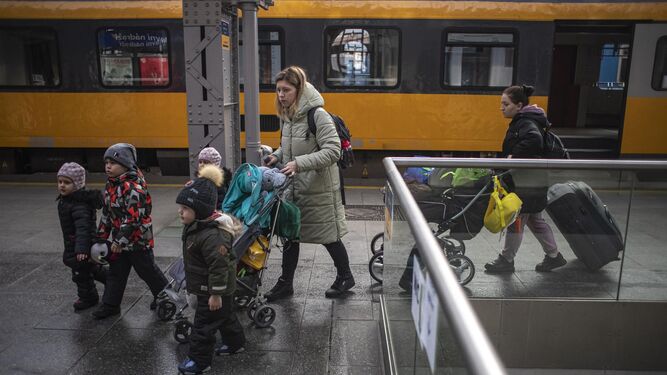 Una mujer y varios niños ucranianos caminan por el andén de la estación de tren de Praga.
