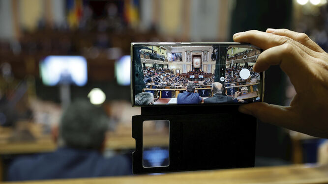 Un diputado toma una foto de las pantallas con Zelenski en el Congreso