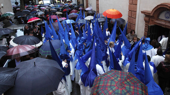 Nazarenos de la Hermandad de Montserrat entre un mar de paraguas.