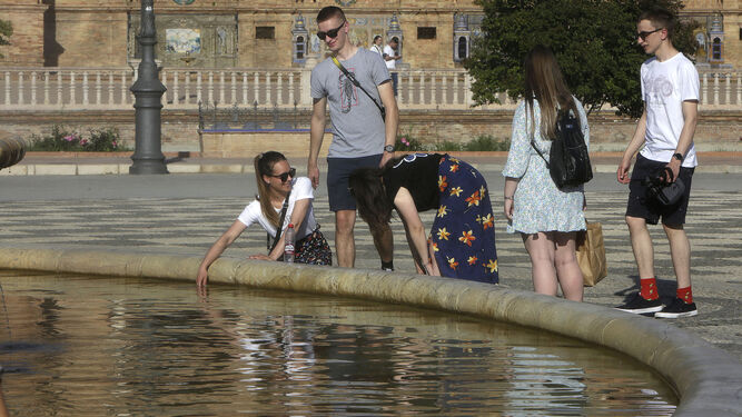 Un grupo de turistas se refresca en la fuente de la Plaza de España.