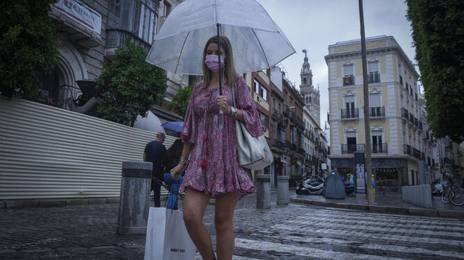 Una mujer pasea por el centro de Sevilla con un paraguas