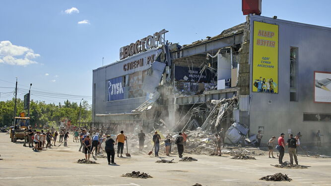 Voluntarios limpian los escombros junto a un centro comercial atacado durante un bombardeo nocturno en Jarkov.