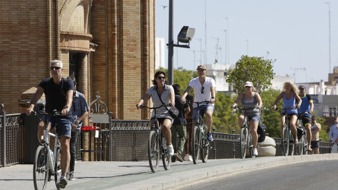 Un grupo de turistas circula por el carril bici del puente de Triana.