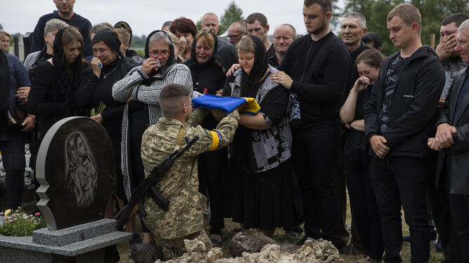 un soldado que entrega una bandera a la madre de un compañero en Novyi Vytkiv .
