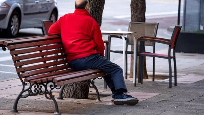 Un hombre sentado en un banco en la calle