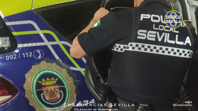 Un policía local de Sevilla introduce al detenido en un vehículo.