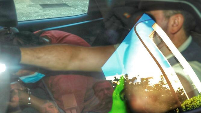 El detenido, con camiseta roja y mascarilla, en el interior del coche camino de los juzgados.
