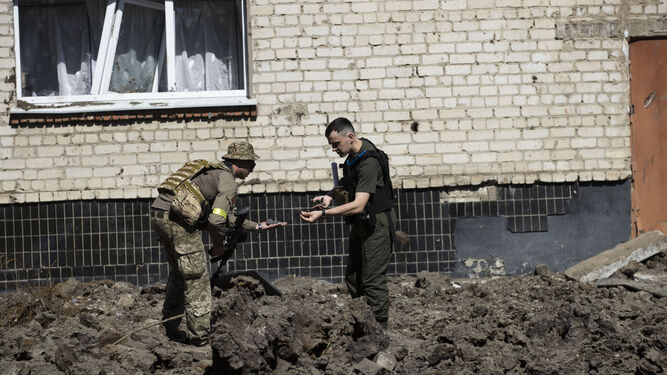 Militares ucranianos recorren el patio de una escuela que fue impactado por un misil ruso de madrugada en Jarkov.