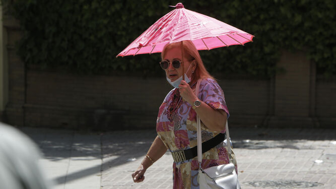 Una mujer se protege del sol con una pequeña sombrilla.