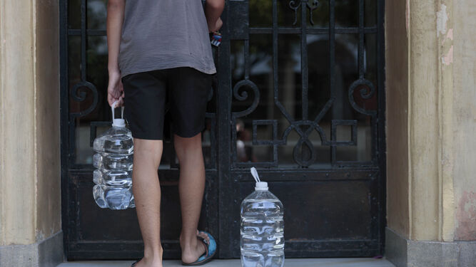 Un joven con dos garrafas de agua.