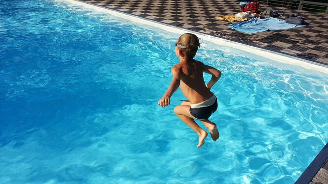 Un niño se lanza de pie a la piscina