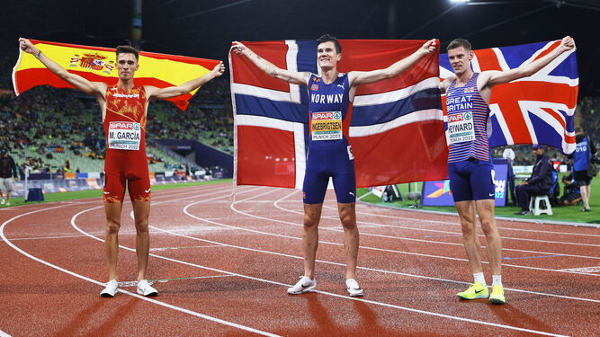 Mario García Romo muestra la bandera española junto al noruego Jakob Ingebrigtsen y el británico Jake Heyward.