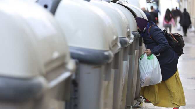 Una mujer rebusca en un contenedor de Málaga.