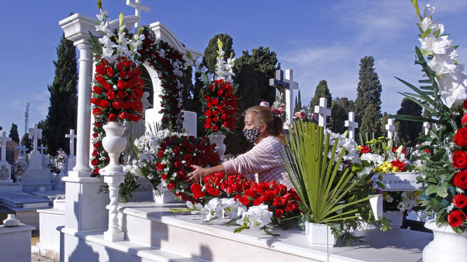 Una mujer coloca flores en la sepultura de un familiar difunto.