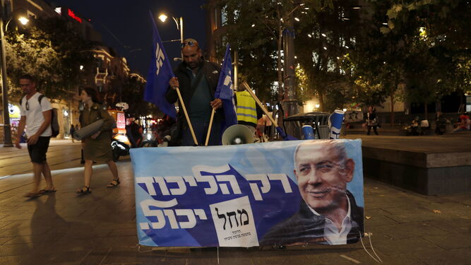 Un seguidor del ex primer ministro israelí Netanyahu despliega un cartel de su campaña en el centro de Jerusalén.