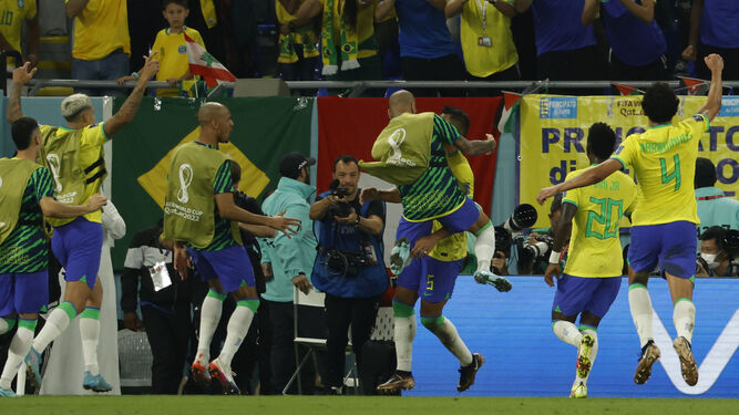 Daniel Alves se abraza eufórico a Casemiro mientras se acercan otros suplentes tras el gol de Brasil.