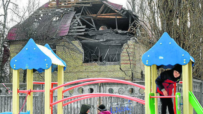 Unos niños juegan en un parque junto a un edificio atacado por Rusia en Kiev.