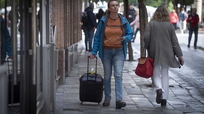 Una turista camina con una maleta y un móvil en la mano por Sevilla.