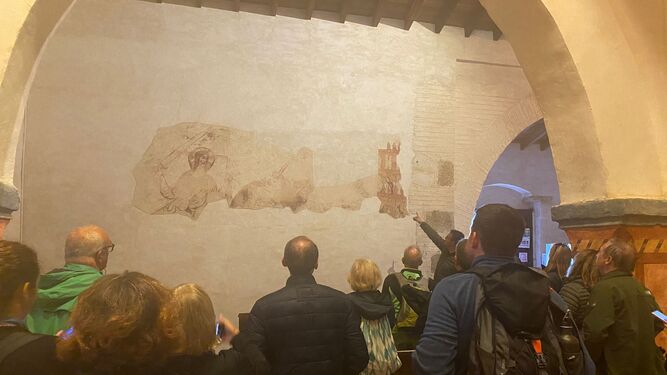 Grupo de turistas mira parte de un fresco.