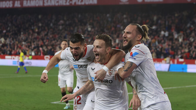 Rakitic celebra su gol de penalti abrazado por Rafa Mir y Gudelj.