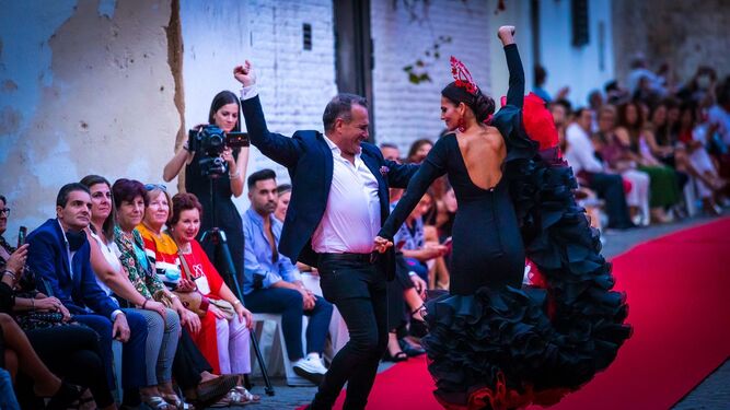 Javier Orozco bailando con una modelo durante un pase de moda flamenca.