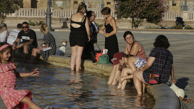 Turistas se refrescan en la fuente de la Plaza de España ante las altas temperaturas del pasado julio en Sevilla.