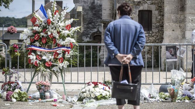Una mujer mira unas flores colocadas en la iglesia de Normandía en la que se produjo un atentado en 2016.