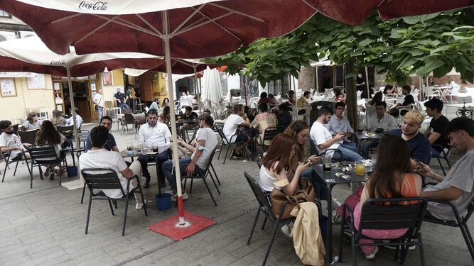Veladores de un bar, en el centro de Sevilla, repleto de clientes.