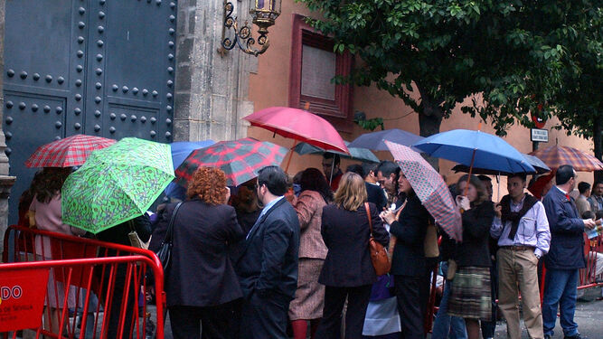 Público esperando, bajo el paraguas, a entrar en la parroquia de San Vicente en Semana Santa.