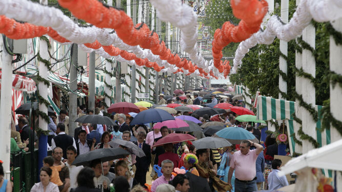 Gente con paraguas en el real de la Feria.