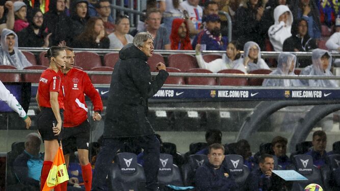 Pellegrini da instrucciones a sus jugadores bajo la lluvia en el Camp Nou.