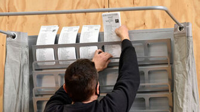 Un trabajador ordena varias papeletas en el dispositivo electoral para los comicios