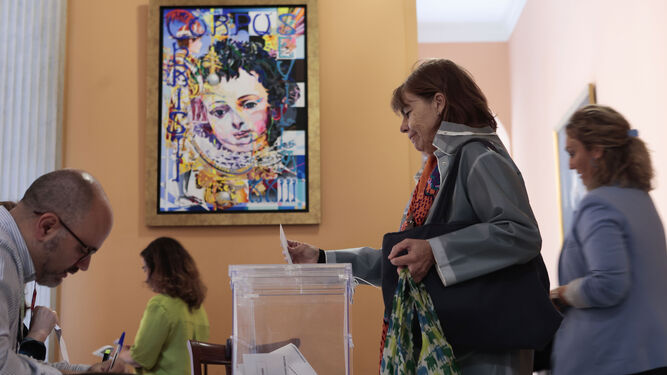 Una mujer deposita su voto en una mesa electoral del Ayuntamiento de Sevilla.