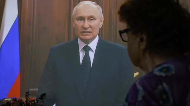Una mujer ve el discurso de Putin en una pantalla.