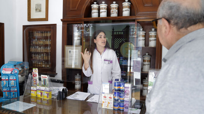 Farmacéutica y paciente sin mascarilla en la Farmacia Gaviño, en el centro de Sevilla.