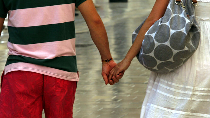 Una pareja se da la mano en la calle.