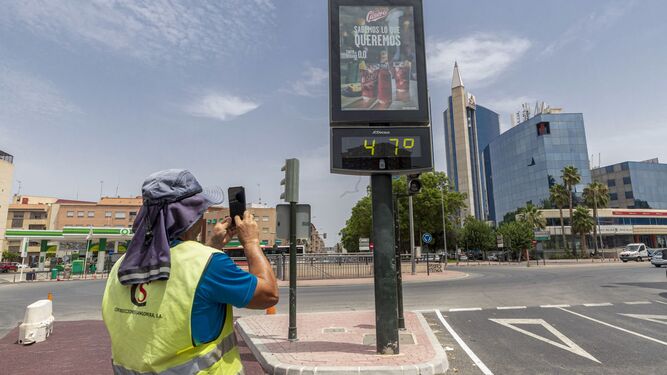 Un hombre fotografía un termómetro que marca 47 grados en la Ronda de Levante de Murcia.