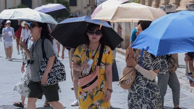 Varias turistas asiáticas se cubren del sol con un paraguas en el centro de Sevilla.