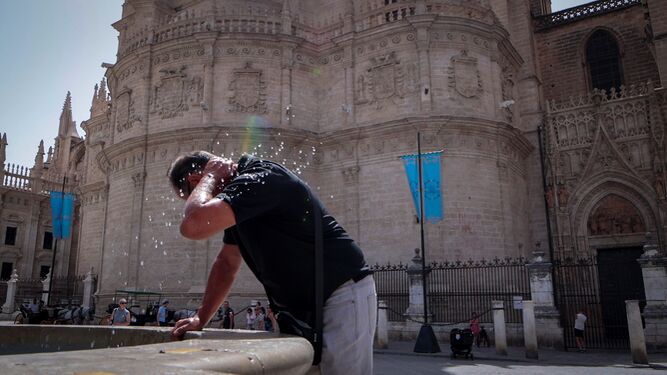 Un turista se refresca con el agua de una fuente junto a la Catedral.