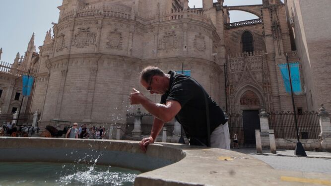 Un turista se refresca con el agua de una fuente junto a la Catedral.