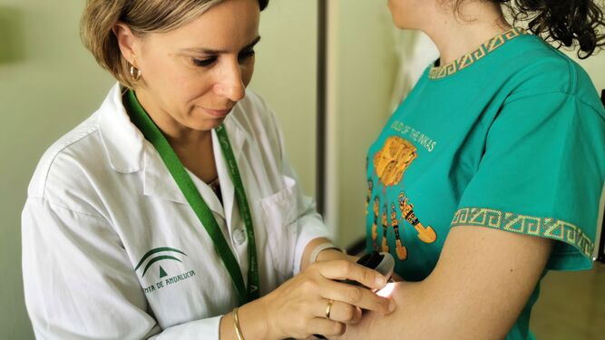 La doctora María coronel revisando a una paciente con el dermatoscopio.