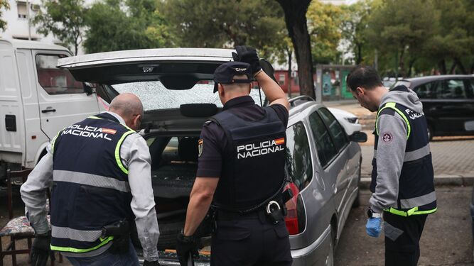 Tres policías nacionales inspeccionan un coche tiroteado en Los Pajaritos, el pasado mes de mayo.