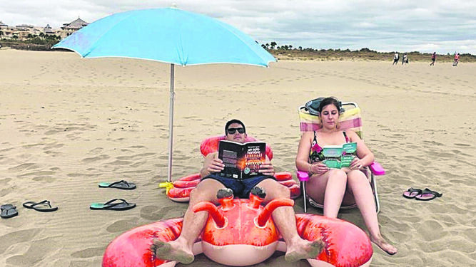 Una pareja lee en la playa de Ayamonte.
