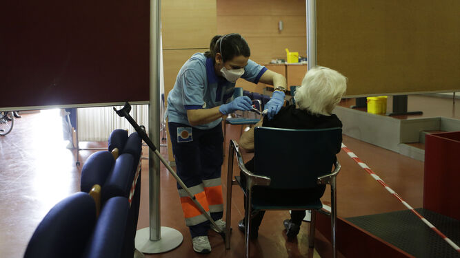 Una sanitaria vacuna a una mujer mayor en Sevilla.