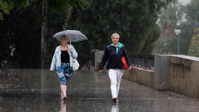 Dos turistas pasean por el centro de la ciudad en plena tormenta.