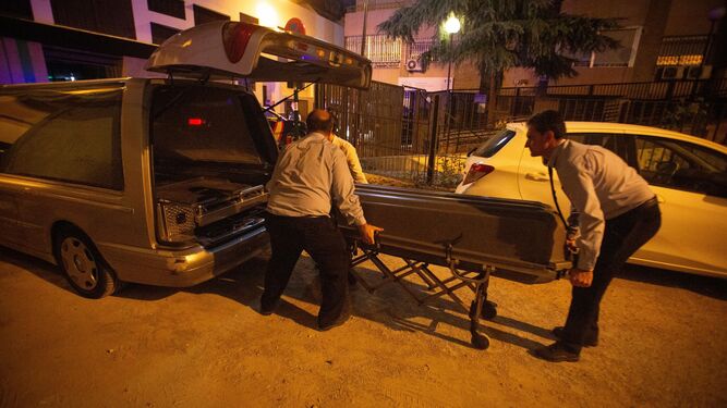 Los empleados de los servicios funerarios con el cadáver de la última mujer asesinada por violencia de género en Granada.