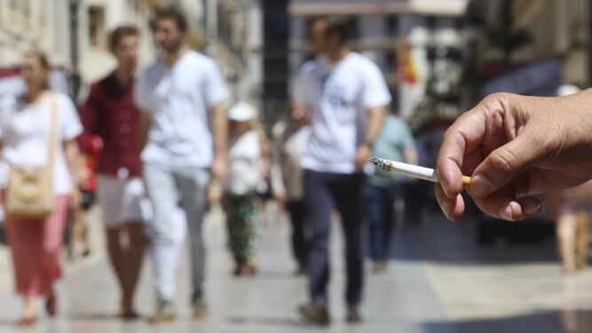 Una persona sujeta un cigarrillo en un espacio público de la ciudad.