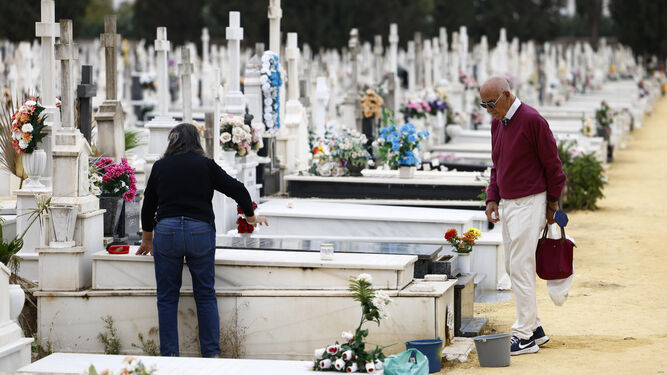 Dos personas adecentan una lápida en el cementerio de San Fernando.