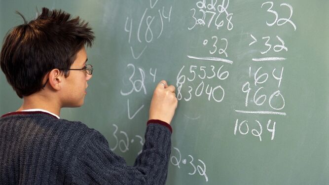 Un alumno de instituto realiza un ejercicio matemático en la pizarra del aula.