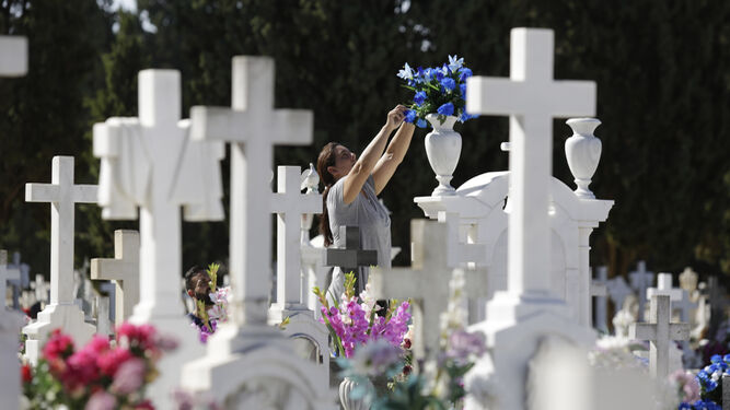 Una mujer coloca flores en una tumba, práctica habitual en vísperas de Todos los Santos.